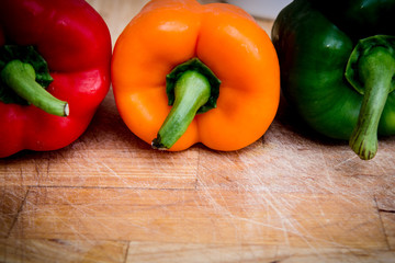 red green and yellow peppers on the chopping board
