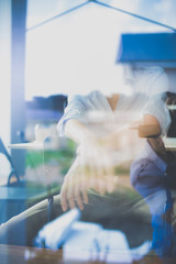 Young woman sitting at office table with laptop,view through window. Young woman