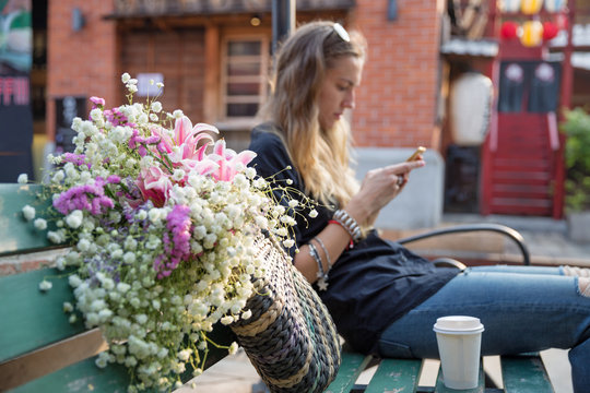 Beautiful woman looking at her phone while sitting outdoors