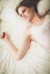 Pretty woman lying down on her bed at home.