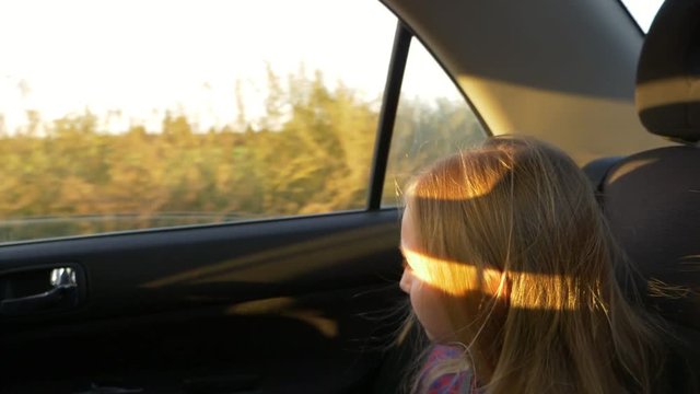 Little caucasian girl traveling in car. Car bounce and shake very much. Handheld shot close up.
