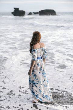 A Woman Stands On Beach Facing Ocean