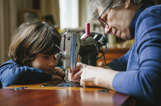 Grandson watching his grandmother working on a sewing machine