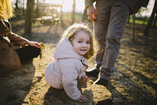 Little girl sitting on the stump looking into the camera
