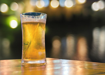 Glass of beer on wood table on black background