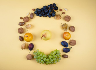 Autumn fruits and nuts on yellow background.