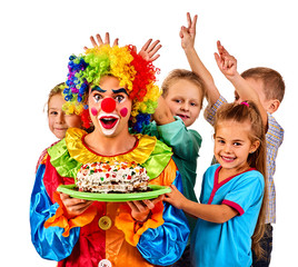 Birthday children clown eating cake with kids together. Celebratory cake on a plate. Fun happy childhood of small group people. Children play with clown.