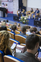 Business Conferences Concept and Ideas. Back of Congress Participants Listening to The Lecturer Speaking In front of the Group of People.