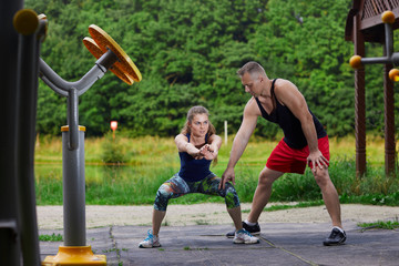 The man the trainer does a training in the park with the girl.