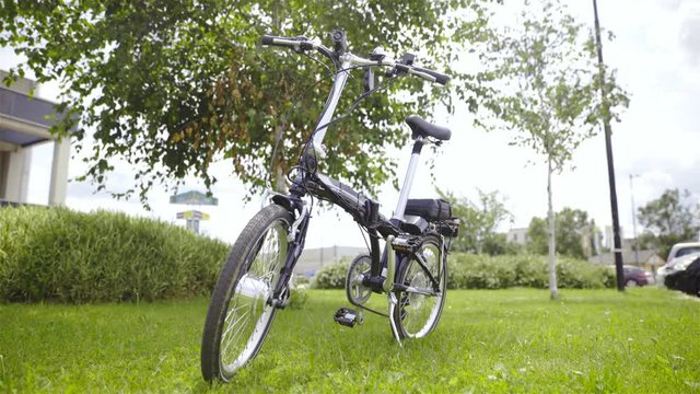 Electric foldable bicycle on grass low angle view 4K