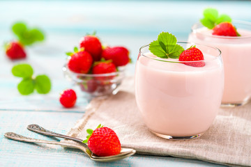 Clear jar of yogurt with strawberries  over on wooden background