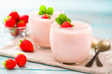 strawberry yogurt and metal spoons on a wooden background