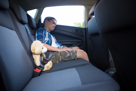 Teenage boy sitting with teddy bear in the car