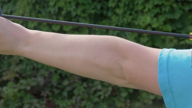 Woman is pulling on bowstring of the bow and shooting. Archery.