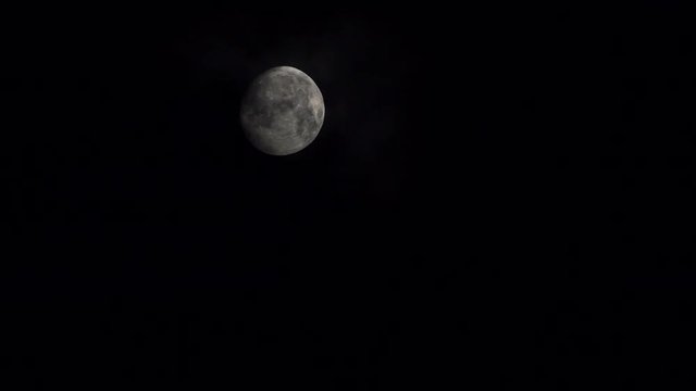 Full moon at night on dark black sky behind moving clouds, moonlight 4K ProRes HQ codec