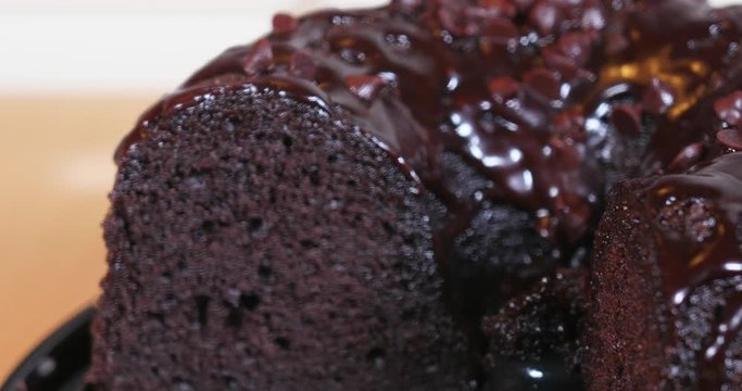 A slow motion close up shot of a person cutting a piece of a chocolate cake.  	