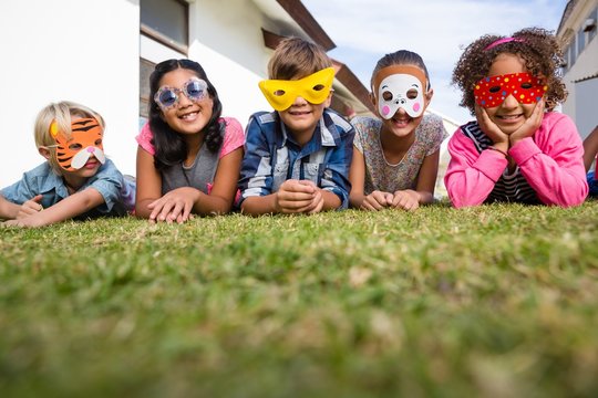 Portrait of children wearing masks lying on field