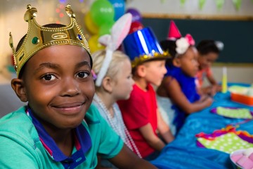 Portrait of smiling boy wearing crown with friends in background
