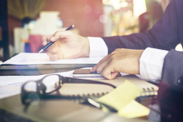 Young business man working in bright office, using laptop, writing notes.