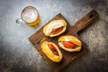 Choripan. Latin American Argentine and chilean food. Grilled chorizo sausages hot dogs served with beer, top view, stone background