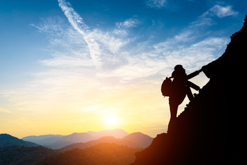 silhouette of climbing man in mountains concept of sports at beautiful sunset - Powered by Adobe