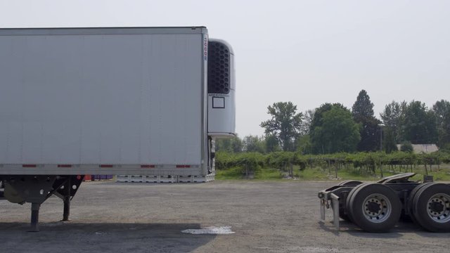 White truck cab reverses and makes connection to white trailer on summer day in rural area. Side view, real-time 4K.