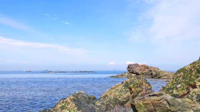 A tide comes: The harmonization in the rock and waves and sky. Camera moves to the left.