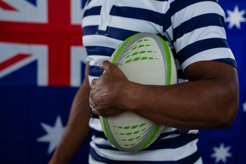 Mid section of male athlete holding rugby ball