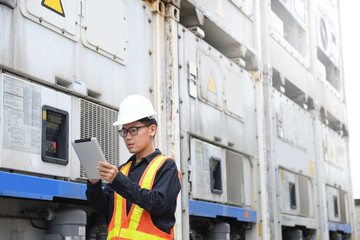 Reefer container technician is using tablet for monitoring temperature of frozen & chill shipments.