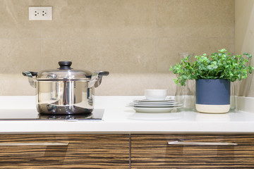 Close-up of stainless steel cooking pot on induction hob in contemporary modern home kitchen.