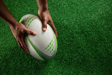 High angle view of hands holding rugby ball - obrazy, fototapety, plakaty