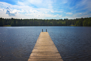 Obraz premium Old pier is on the lake in the forest