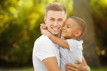 Young man with adopted African American boy outdoors