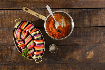 Raw dish ratatouille in pan on wooden table, top view