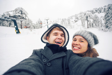 Fototapeta na wymiar Young man and woman taking a selfie in winter using smart phone.