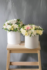 Beautiful tender bouquet of flowers in white box on gray ackground with space for text