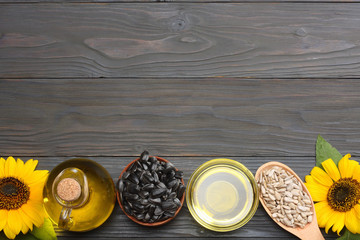 Sunflower oil, seeds and flower on dark wooden background. top view with copy space