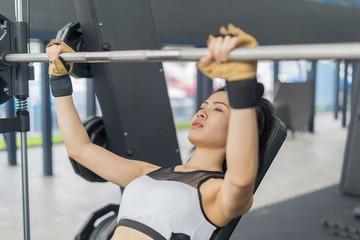 Fitness woman in training showing exercises with barbells in gym
