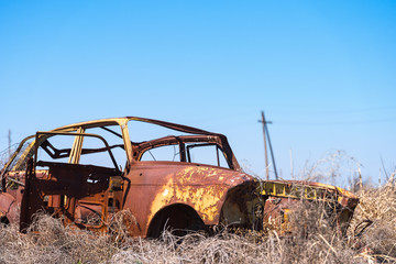 Abandoned and rusty wreckage of a vintage Soviet Russian car in the middle of dry hay with scenic mountains and blue sky on the background in rural Southern Armenia in Ararat province on 4 April 2017.