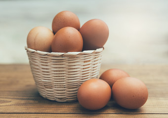 Fresh eggs in white basket on wooden background