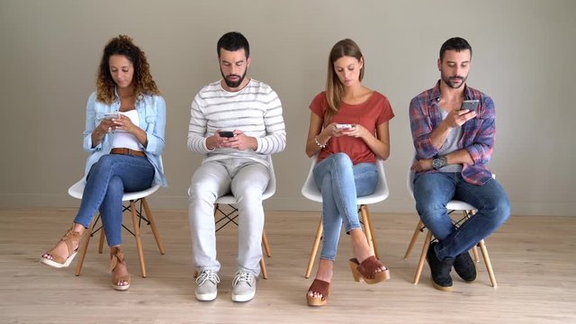 Young people in waiting room using smartphones