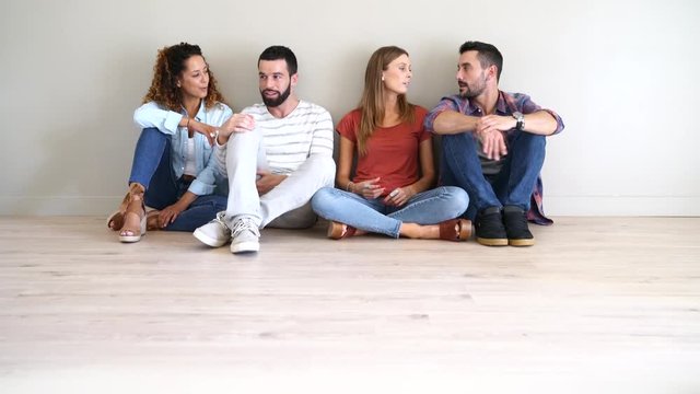 Group of friends sitting on floor and talking together