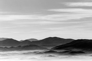 Widok z góry na dolinę wypełnioną morzem mgły, z różnymi warstwami wschodzących wzgórz i gór - 172309572