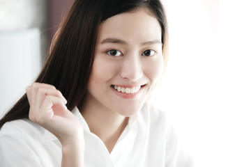 Portrait of smiling asian woman  in white shirt and long hair, close up