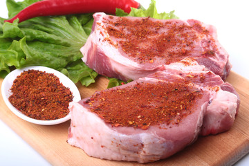 Raw pork chops with herbs and spices on cutting board. Ready for cooking.
