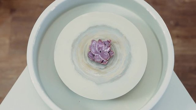 The clay product rotates on a potter's wheel. Purple lily. Top viem.