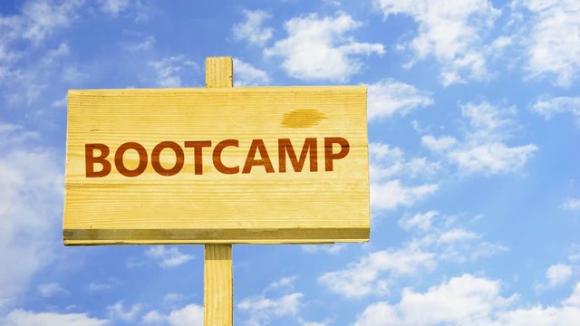 Bootcamp word on a wooden sign against time lapse clouds in the blue sky. 