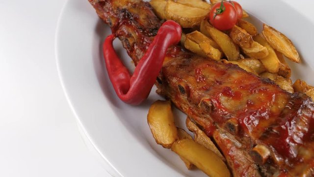 Grilled ribs in sauce with potatoes, tomatoes and chili pepper, served in Restaurant or Pub, 4K, ProRes codec, 422 HQ, ISO 100