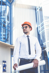 The builder with a paper stand on the background of the business center