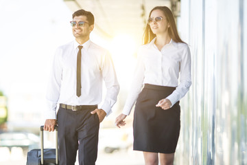 Fototapeta premium The business man and woman in sunglasses walk with a suitcase